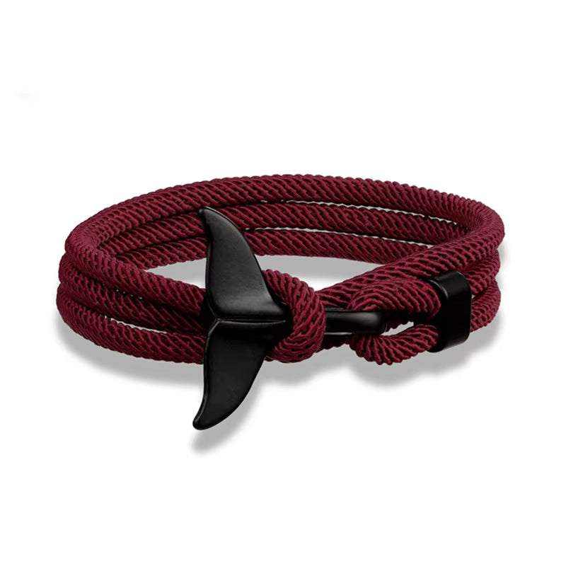 Close-up of a multilayered nautical whale tail and anchor bracelet with adjustable braided rope band for women